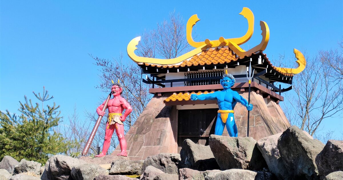 赤鬼と青鬼の像と特徴的な屋根の建物の風景
