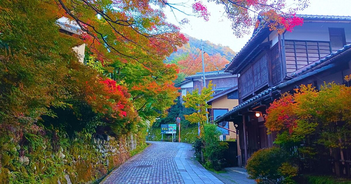 紅葉に彩られた石畳の道と古民家の風景