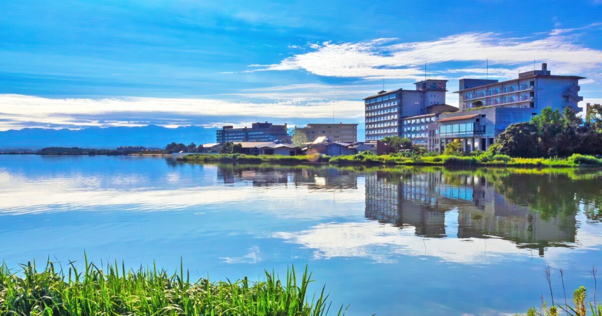 湖面に映る片山津温泉の宿泊施設群と青空