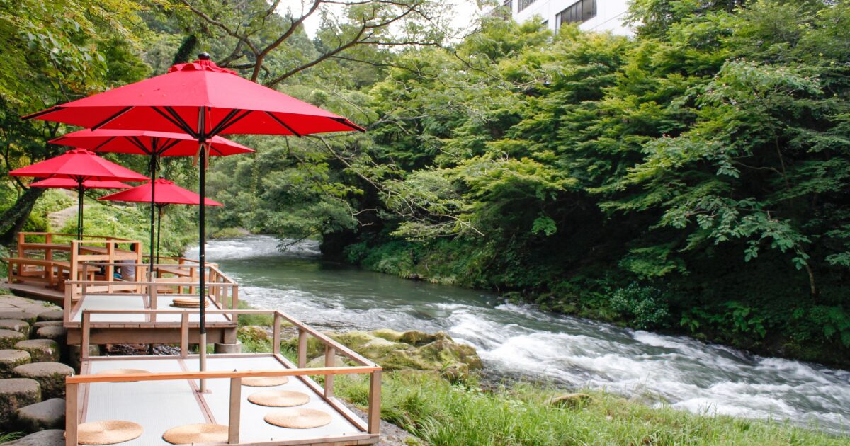 川沿いに設置された赤い和傘と座敷席の風景