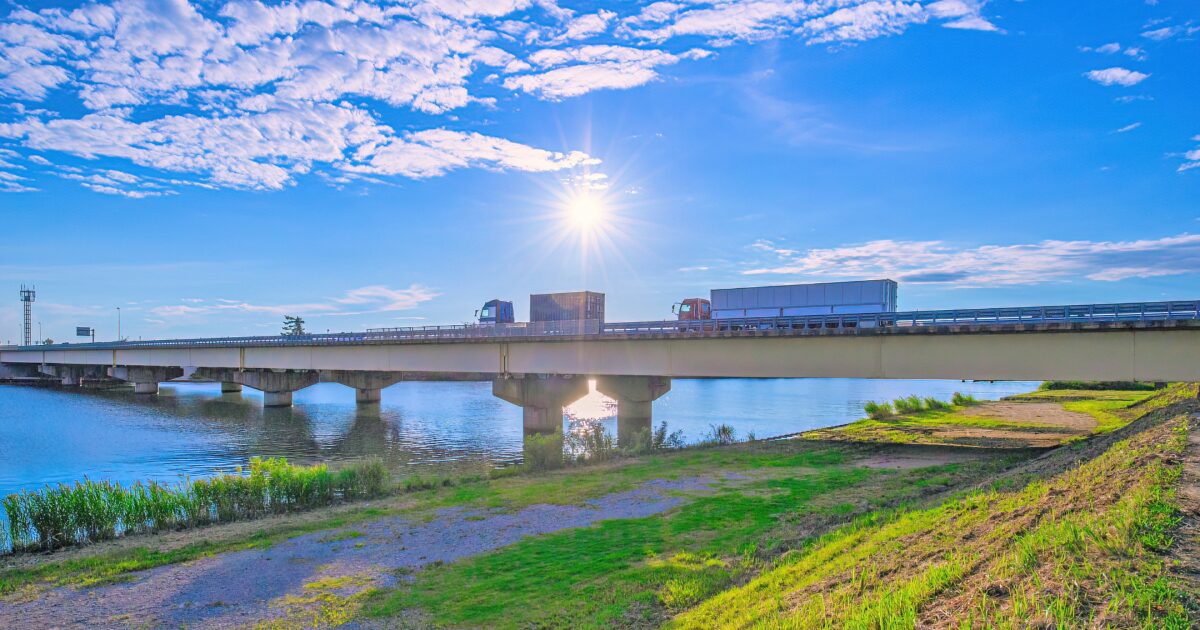 晴天の下でトラックが走る川に架かる橋